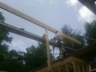 Carpenter setting a ridge beam over a new addition frame — Ice Dam Removal by Roofing Brothers in Moyock