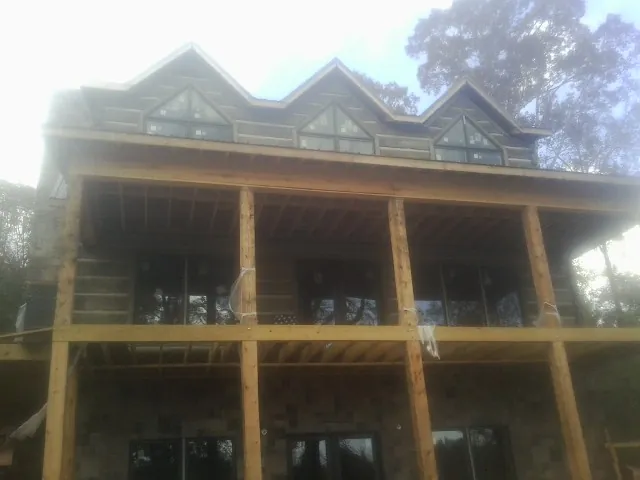 Dormers and porch framing on a large log home under construction — Roof Coating work by our crew in Moyock