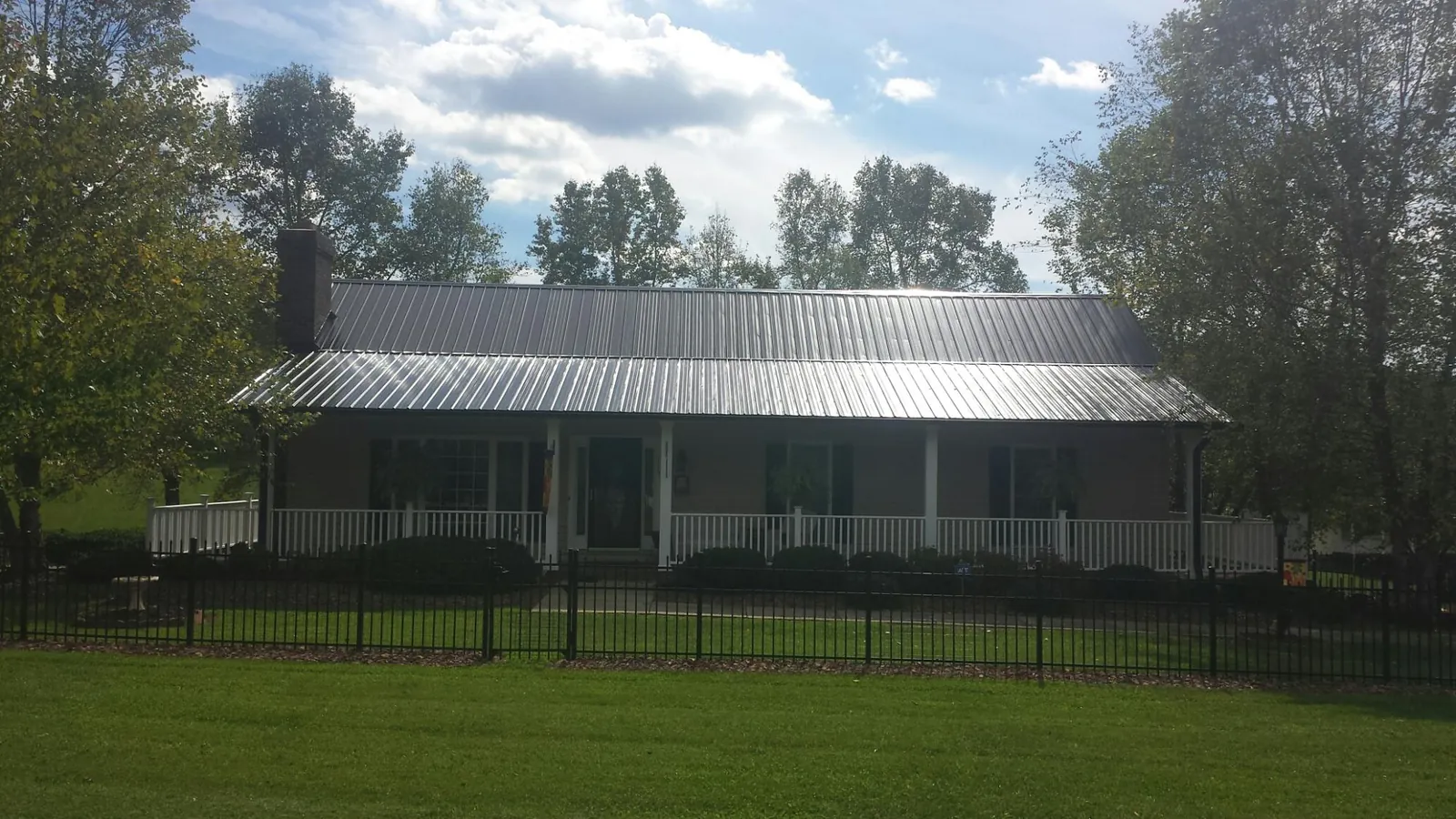 Gray metal roof on a brick ranch with a full width front porch — Gutter Guard Installation work by our crew in Moyock