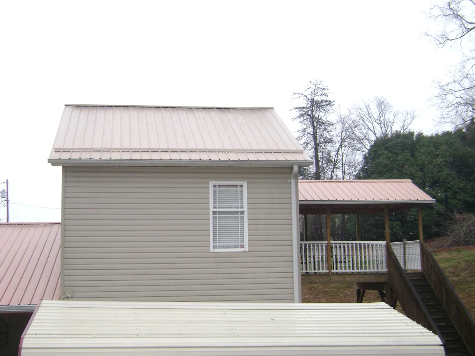 Tan metal roofs on a two story addition and attached porch, from a Roof Replacement job in Moyock