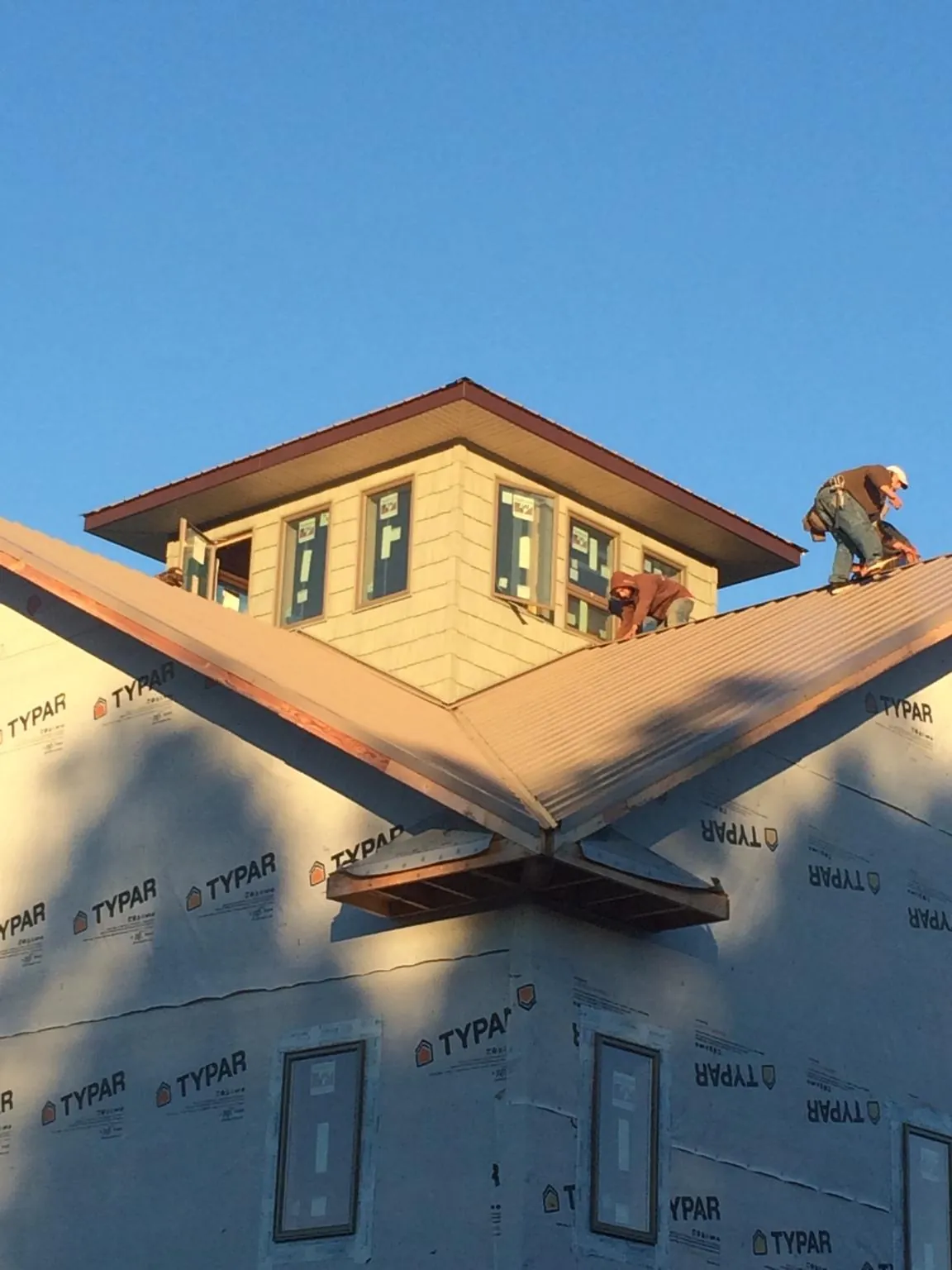 Roofers working around a rooftop cupola on a new metal roof at sunset — Roof Waterproofing in Moyock by Roofing Brothers